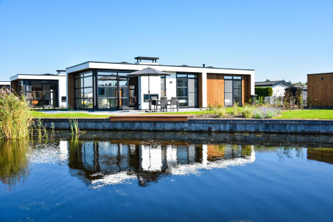 Villa moderna junto al agua, con ventanas de vidrio y terraza en MarinaPark Residentie Nieuw Loosdrecht, Países Bajos.
