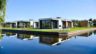 Modernas villas frente al agua en Villa Nautica Lodge, rodeadas de naturaleza y reflejadas en el agua tranquila.
