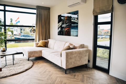 Sala moderna en Villa Nautica, MarinaPark Residentie Nieuw Loosdrecht, Países Bajos, con sofá claro.