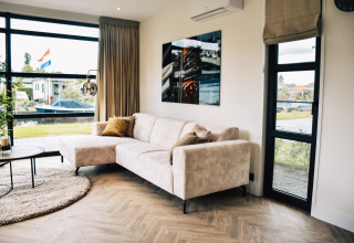 Sala moderna en Villa Nautica, MarinaPark Residentie Nieuw Loosdrecht, Países Bajos, con sofá claro.