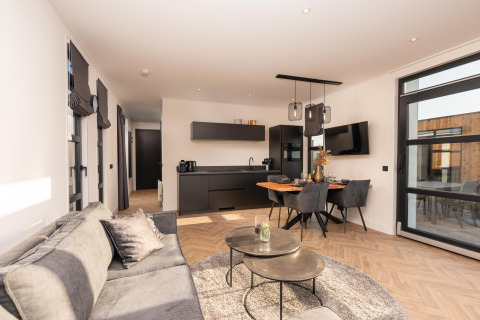Helles, modernes Wohnzimmer in der Villa Nautica Lodge mit offener Küche, Essbereich und Sofa.