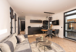 Sala de estar luminosa y moderna en Villa Nautica lodge, con cocina abierta, mesa de comedor y sofá.