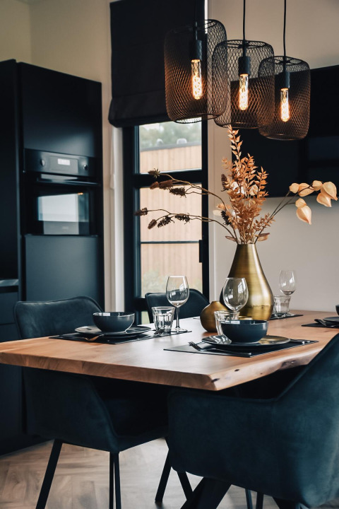 Moderne eetruimte met houten tafel, zwarte stoelen en verlichting bij Villa Nautica, Nieuw Loosdrecht.