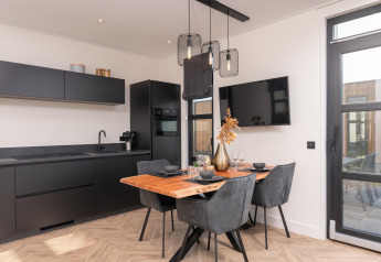 Moderne lodgekeuken en eethoek in Villa Nautica met zwart design, houten tafel en stijlvolle lampen.