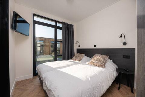 Dormitorio moderno en Villa Nautica con dos camas, grandes ventanas y vista exterior, MarinaPark, Países Bajos.