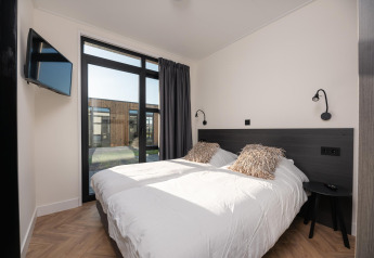Chambre moderne à la Villa Nautica avec lits jumeaux, grandes fenêtres et vue extérieure, MarinaPark, Pays-Bas.