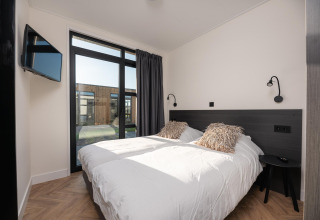 Dormitorio moderno en Villa Nautica con dos camas, grandes ventanas y vista exterior, MarinaPark, Países Bajos.