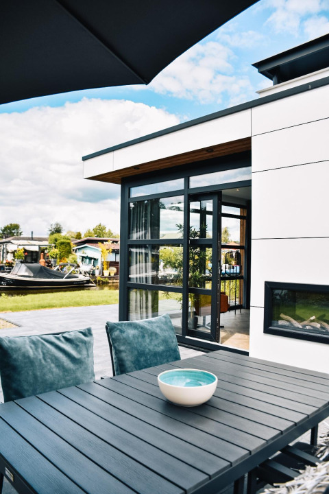 Buitenterras met moderne tafel aan Villa Nautica, MarinaPark Residentie Nieuw Loosdrecht, Nederland, zonneschijn.
