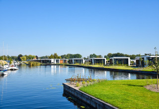 Lodge Villa Nautica con casas modernas junto al agua, barcos y un área verde en un día soleado.