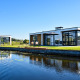 Moderne Villa Nautica-lodges med store vinduer, terrasse og vandudsigt under en klar blå himmel.