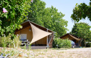 Tiendas safari en Villatent Nomad en Camping Les Bois du Bardelet, Francia, rodeadas de árboles verdes.