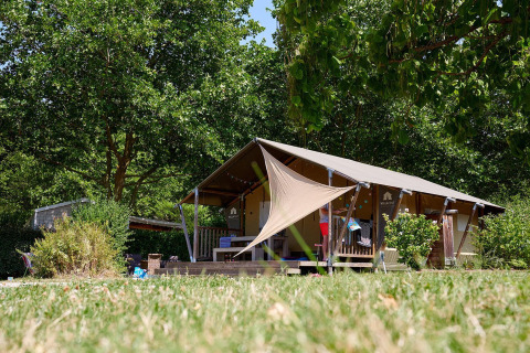 Tienda safari Villatent Nomad en Camping Les Bois du Bardelet en Francia, rodeada de árboles y naturaleza.