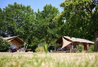 Safari tents at Villatent Nomad in Camping Les Bois du Bardelet, France, surrounded by greenery and trees.