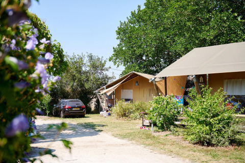 Tienda safari Villatent Nomad en Camping Les Bois du Bardelet, Francia, con coche y vegetación.