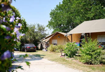 Safari tent Villatent Nomad bij Camping Les Bois du Bardelet in Frankrijk, met auto en groen.
