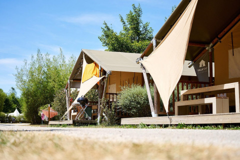 Tiendas safari Villatent Nomad en Camping La Roche d’Ully, Francia, rodeadas de vegetación y sol.