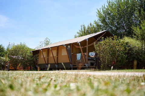 Safari tent Villatent Nomad at Camping La Roche d’Ully in France, surrounded by greenery and blue sky.