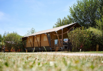 Tienda safari Villatent Nomad en Camping La Roche d’Ully, Francia, rodeada de vegetación y naturaleza.