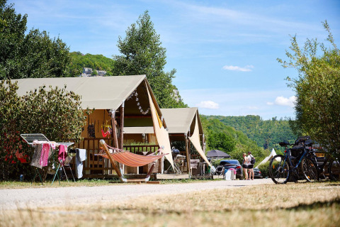 Tienda safari Villatent Nomad en Camping La Roche d’Ully, Francia, con hamaca y paisajes verdes.