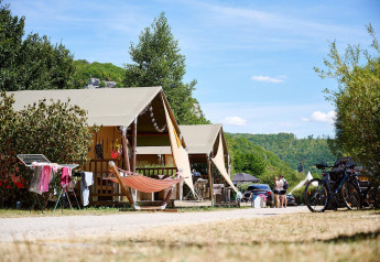 Tienda safari Villatent Nomad en Camping La Roche d’Ully, Francia, con hamaca y paisajes verdes.