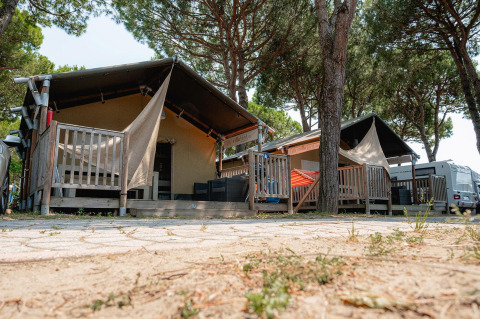 Villatent Nomad safari tent at Camping Village Cavallino in Italy, nestled among pine trees and wooden decks.