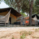 Tienda safari Villatent Nomad en Camping Village Cavallino, Italia, rodeada de pinos y terrazas de madera.