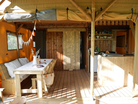 Interior de alojamiento glamping con muebles de madera, mesa de comedor, cocina y ambiente acogedor.
