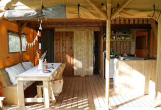 Interior de alojamiento glamping con muebles de madera, mesa de comedor, cocina y ambiente acogedor.
