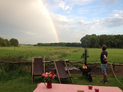 Uomo guarda un arcobaleno sopra un prato al parco vacanze Feather Down De Lange Weide, Drenthe, Paesi Bassi.