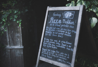 Buitenbord met info over pizza bakken bij Feather Down De Lange Weide vakantiepark in Drenthe, Nederland.