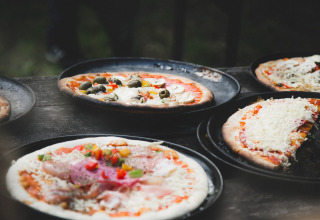 Friske hjemmelavede pizzaer med forskellige toppings serveres på bakker i ferieparken De Lange Weide i Drenthe.