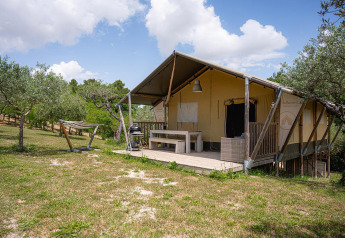 Safari-Zelt Villatent Nomad auf Camping Pian Di Boccio in Italien, mit Veranda und Hängematte im Grünen.