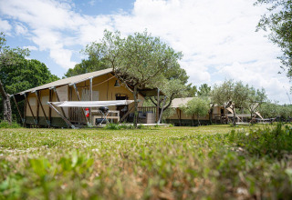Tiendas safari Villatent Nomad en Camping Pian Di Boccio, Italia, rodeadas de árboles y cielo despejado.