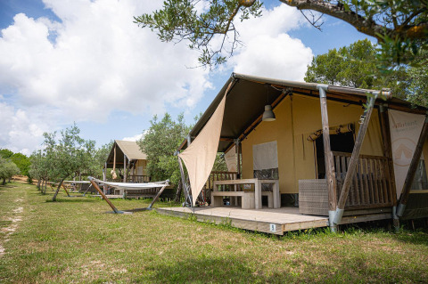 Tenda safari Villatent Nomad al Camping Pian Di Boccio in Italia, con amache e veranda in legno.