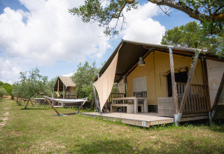 Tienda safari Villatent Nomad en Camping Pian Di Boccio, Italia, con hamacas y terraza de madera.