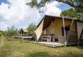 Tenda safari Villatent Nomad al Camping Pian Di Boccio in Italia, con amache e veranda in legno.