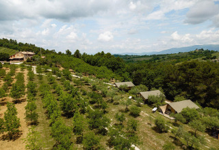 Vista aérea de tiendas safari Villatent Nomad en un campo verde de Camping Pian Di Boccio, Italia.