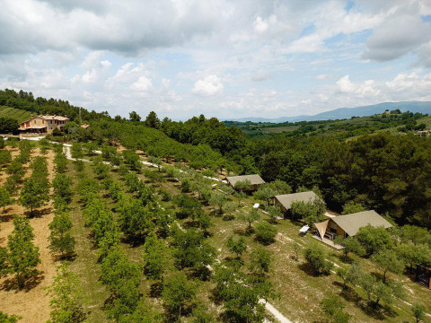 Vista aérea de tiendas safari Villatent Nomad en un campo verde de Camping Pian Di Boccio, Italia.