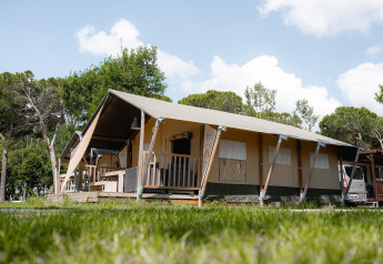 Tienda safari Villatent Nomad en Camping Punta Navaccia, Italia, rodeada de vegetación y cielo azul.