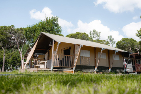 Safari-teltet Villatent Nomad på Camping Punta Navaccia i Italien med træer og blå himmel omkring.