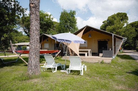 Safaritent Villatent Nomad met ligstoelen, parasol en hangmat op Camping Punta Navaccia in Italië.