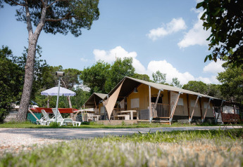 Tienda safari Villatent Nomad en el Camping Punta Navaccia en Italia con tumbonas y sombrilla afuera.