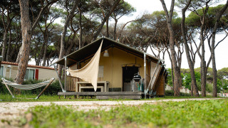 Tenda safari Villatent Nomad al Camping Roma Capitol in Italia, circondata da pini e un'amaca.