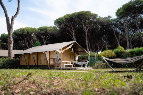 Tienda safari Villatent Nomad en Camping Roma Capitol, Italia, rodeada de árboles y naturaleza verde.