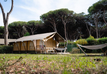 Tente safari Villatent Nomad au Camping Roma Capitol en Italie, entourée d’arbres et de verdure.