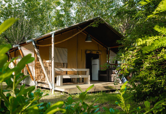 Tente safari Villatent Nomad au Camping La Chiocciola en Italie, entourée de verdure et d'arbres.