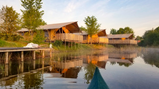 Safari tents by the lake at Holiday Park Eigen Wijze in the Netherlands, viewed from a canoe on water.