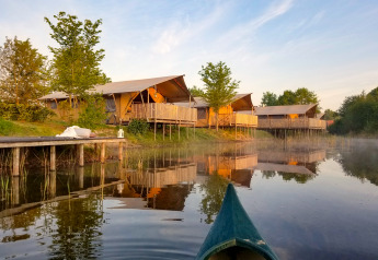 Safari tents by the lake at Holiday Park Eigen Wijze in the Netherlands, viewed from a canoe on water.