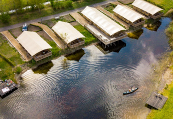 Aerial view of safari tents by the lake at Holiday Park Eigen Wijze, Netherlands, with a canoe.