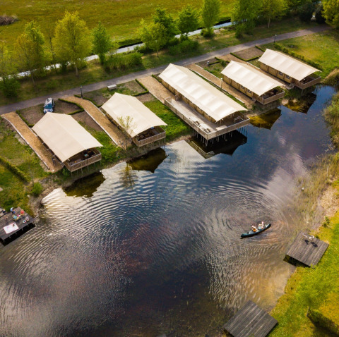 Vue aérienne des tentes safari près d’un lac au Holiday Park Eigen Wijze, Pays-Bas, avec un canoë.